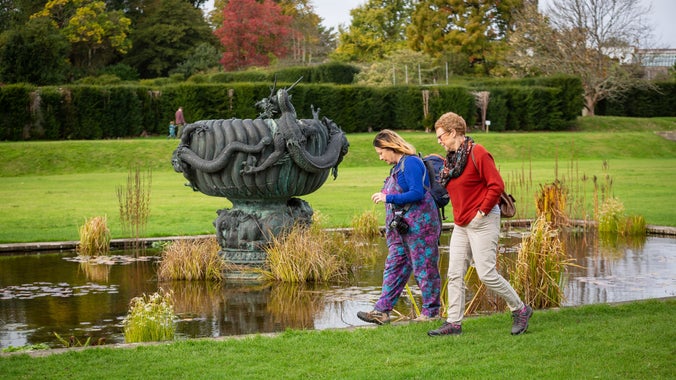 A couple walk along the canal on the South Lawn in the autumn at Dyffryn Gardens, Vale of Glamorgan